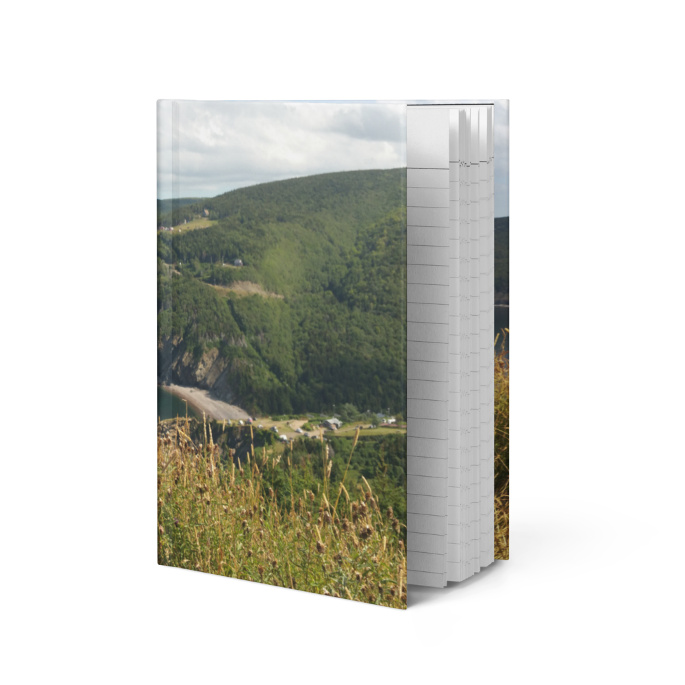 Partially open hardcover journal showing lined pages and Nova Scotia coastal photo cover